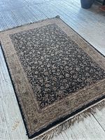 Full view of the vintage rectangular area rug with floral pattern and fringe, showing overall design and color scheme.