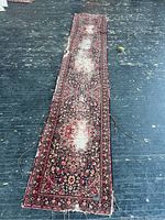 Full view of vintage rug carpet runner laid flat on dark floor showing length and wear areas