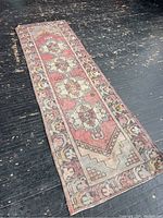 Full view of the vintage runner rug on a dark wooden floor showing overall condition and pattern details.