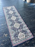 Full view of the vintage runner rug laid flat to show its size, design, and condition.