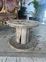 Front view of the wooden spool showing top and base, and cracks in the wood.