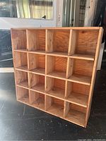 Front image showing entire wood shelving unit with 16 cubbies in a 4 by 4 arrangement.