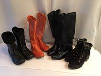 Four pairs of women's boots on white background: black Bogs rain boots, orange mid-calf boots, black tall leather boots, black lace-up ankle boots with fur lining.
