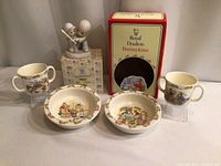 Photo showing 2 Bunnykins cups with handle, 2 bunny-themed bowls, and a boxed Precious Moments figurine of two children playing baseball.