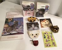 Full lot overview showing cat photo albums, calendar, multiple cat-shaped purses, stickers, cat photo card, and cat head figurine.