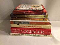 Stack of nine cookbooks showing titles and colorful food covers: 301 Essential Tips Cooking with Vegetables, Desserts, Breakfast Fruit Dessert, Pasta Sfoglia, The Complete Vegetarian Cookbook, The Culinary Arts Institute Cookbook, Homlyn All Colour Book of Puddings & Desserts