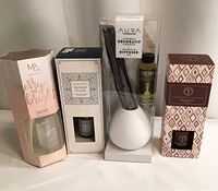 All four reed diffusers in original packaging lined up side-by-side showing packaging and branding