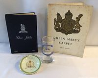 Four Royal Family memorabilia items including two books, a commemorative glass, and a porcelain pin dish with royal insignia.
