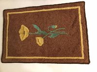 Full view of the vintage hook rug showing the entire yellow flower design on a brown background with yellow border lines.