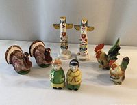 Photo showing entire lot including two turkey shakers, two totem pole shakers, man and woman set, and rooster set.