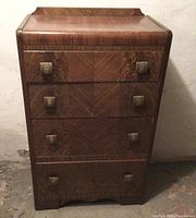 Front view of the vintage tallboy dresser showing four drawers with chevron wood grain and metal handles.