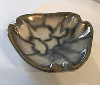 Top-down view showing metallic finish and organic shape of the ashtray.