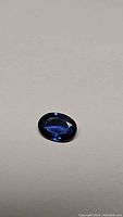 Oval faceted sapphire, face-up, on neutral background