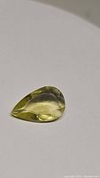 Clear photo of the 6.02 carat pear cut lemon citrine gemstone showing its lemon-yellow color and faceted pear shape.