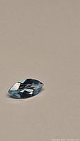 Close-up photo of natural sky blue topaz marquis cut gemstone showcasing its color, cut, and clarity on a neutral background.