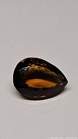 Pear-shaped faceted Madeira citrine gemstone displaying deep cognac color and excellent clarity on a neutral background.