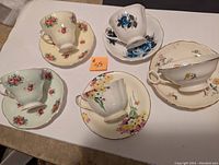 Photo showing five tea cups upside down on matching saucers with varied floral patterns and colors