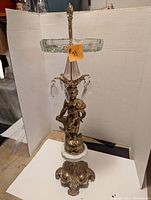 Front view of the tall stand-up ashtray showing the cherub figure, hanging crystals, and glass ashtray top with 8-inch diameter.