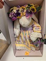 Soft plush bunny doll dressed in floral dress with flower crown inside the box