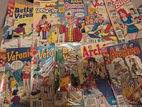 Photo of 10 Archie comics including Betty, Veronica, Archie, and Cherry Blossom titles arranged in two rows. Comics are in plastic sleeves, covers are colorful and in excellent condition.