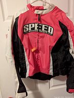 Front view of the pink, black, and white SPEED motorcycle jacket with zipper and branding on chest.