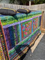Quilt draped showing vibrant colors and matching pillows on top.