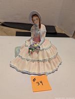 Full view of Royal Doulton Day Dreams figurine showing seated woman in pink and white dress with bouquet.