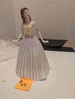 Full view of the Royal Doulton figurine showing the figure in a lavender and pale yellow dress in standing pose.