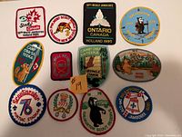 Top-down image showing 12 embroidered scouting badges arranged in three rows, featuring different scouting events from Canada and Ontario from 1976 to 1999.