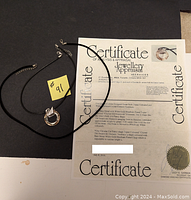 Two swan style crystal element necklaces shown with jewellery appraisal certificate.