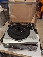 Silver USB turntable with dust cover on top of original box on surface.