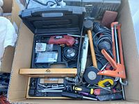 Top view of box with assorted hand tools and power tool kit including rotary tool, mallet, clamps, screwdrivers, tape measure, and level.