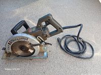 Side angle image of the Black and Decker skill saw showing its blade, rear handle, and power cord.