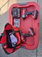 Photo showing entire lot including cordless drill and impact driver with batteries attached, battery charger, drill bit set, red carrying bag and large red plastic tub all branded Craftsman.