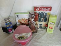 Full view of kitchen items lot showing guacamole bowl, cutlery set, blender, baking dish, leftovers containers, and coffee decor.