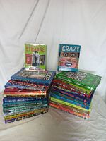 Lot showing 24 books including two Ripley Believe It or Not hardback books and many Guinness World Records books stacked in two piles.