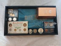 Overview photo showing entire lot in black display tray including coin set, loose coins, pouch, and box.