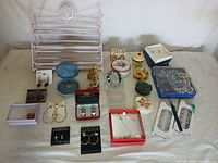 Full lot of assorted jewelry displayed on table with a pink metal rack and several boxes.