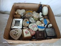Top-down view of the full lot inside a cardboard box showing various trinket and jewelry boxes of different shapes and materials