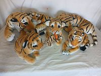 Full group photo of five plush tiger toys in various poses showing size differences and baby tigers included.