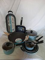 Full lot of blue non-stick cookware showing assortment of pots, pans, lids with varied handles.
