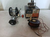 Three vintage fly-fishing reels displayed with a Langley branded box and fishing line.