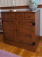 Front view of Ethan Allen cabinet showing three drawers above two louvered doors with black hardware