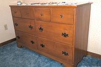 Full front angle view of Ethan Allen Baumritter eight drawer dresser in maple tone on a blue carpet floor.
