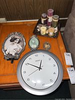 Overview photo showing Seiko wall clock, three metal decorative frames, and ceramic plate with candles on a wooden table
