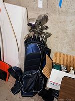 Full view of golf bag caddy in blue color filled with golf clubs, showing club heads and bag details.