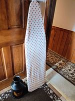 Full view of ironing board with floral fabric cover and Hood milk can on floor, showing relative size and condition.