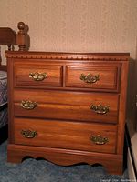 Front view of the Lea wooden dresser showing four drawers with brass handles, highlighting the wood grain and decorative molding.