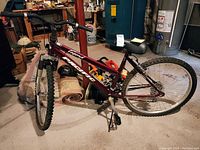 Side view of the red and black Pacific mountain bike showing the full profile, knobby tires, suspension system, and rusty chain.