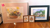 Photo showing two framed watercolor paintings and two small framed dried flower bouquet artworks on floor against wall.